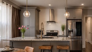 A modern kitchen with a central island, stainless steel appliances, and pendant lighting. - Welcome to our stylish executive 3-bedroom condo in the heart of Central Dallas. Enjoy a fully equipped kitchen and spacious dining area, perfect for cooking and entertaining. (Dallas)