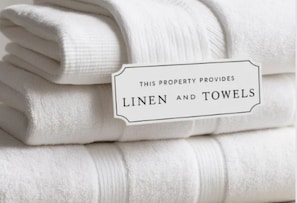 A stack of white towels with a label stating 'THIS PROPERTY PROVIDES LINEN AND TOWELS.'
