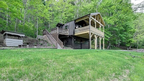 A rustic cabin with a wooden deck and a staircase leading to a second-story balcony. - Creekside Cabin: Tubing, Trails & Highlands Charm! (Highlands)