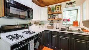 A modern kitchen with a gas stove, microwave, and dark cabinetry. - Creekside Cabin: Tubing, Trails & Highlands Charm! (Highlands)