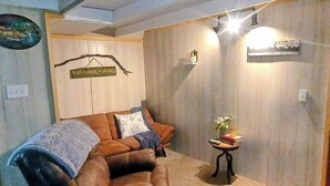 Un accogliente soggiorno con un divano in pelle marrone, un tavolino con un vaso e libri, e un cartello appeso al muro.
