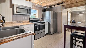 Una cucina moderna con elettrodomestici in acciaio inossidabile, travi a cassetto in legno e un'ampia finestra.
