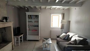 En stue med sofa, lille bord, bogreol og et vindue med lampe.