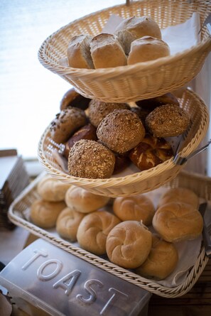 A multi-tiered basket filled with various types of bread, including rolls and buns, displayed on a table with a sign that reads "TOAST". - Landgasthof zur Sonne (Dillingen an der Donau)