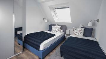 A bedroom with two beds, a skylight, and a mirror.