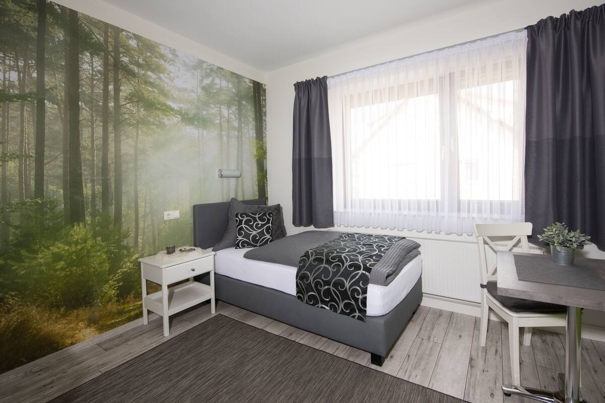 Ein Schlafzimmer mit einem Bett, einem Nachttisch, einem Schreibtisch und einem Stuhl.
