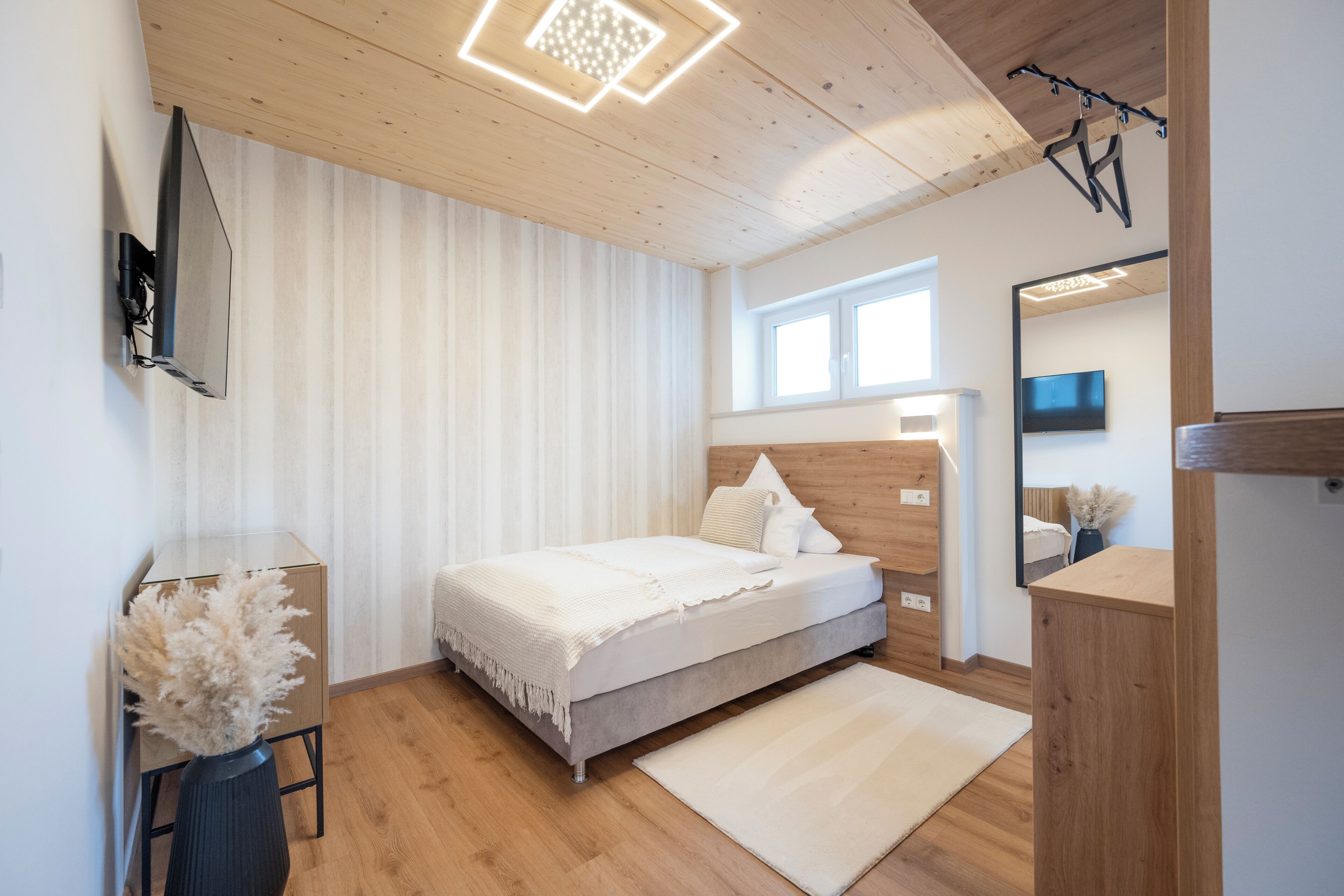 Um quarto moderno com uma cama, uma escrivaninha, uma cadeira, um espelho e uma janela.
