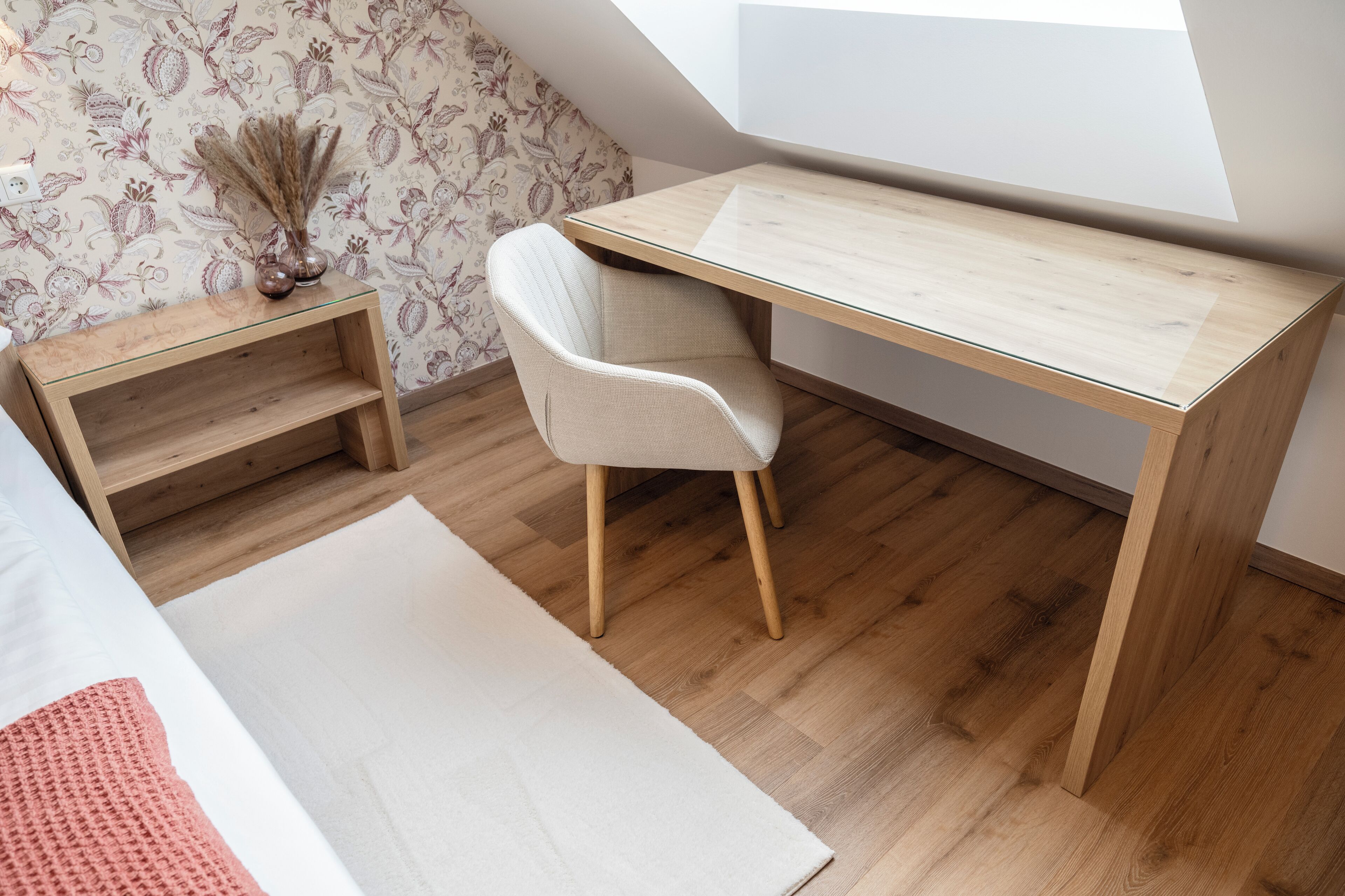 Une petite pièce moderne, avec un bureau en bois, une chaise blanche et une étagère en bois.
