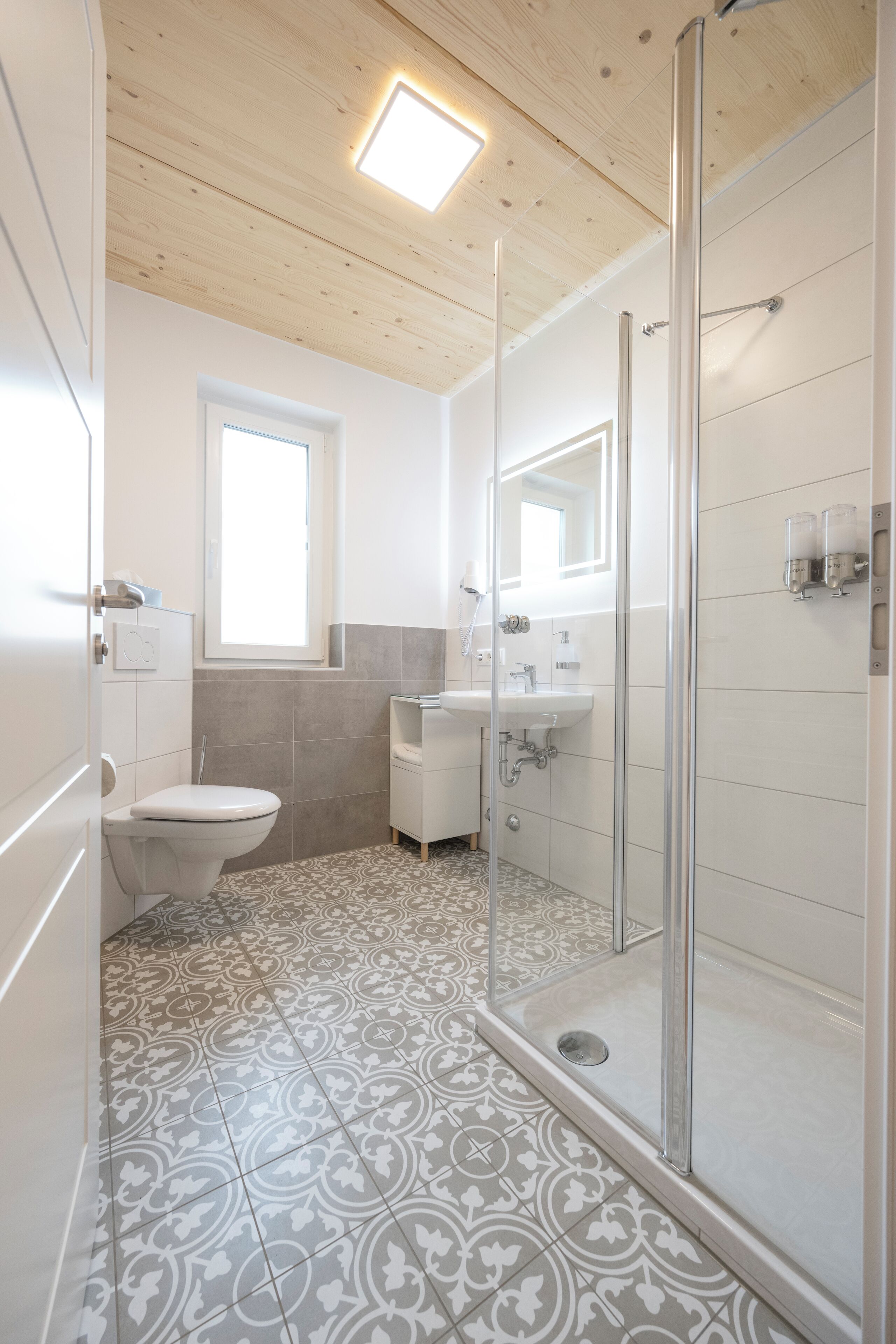 A modern bathroom with a shower, toilet, and sink.