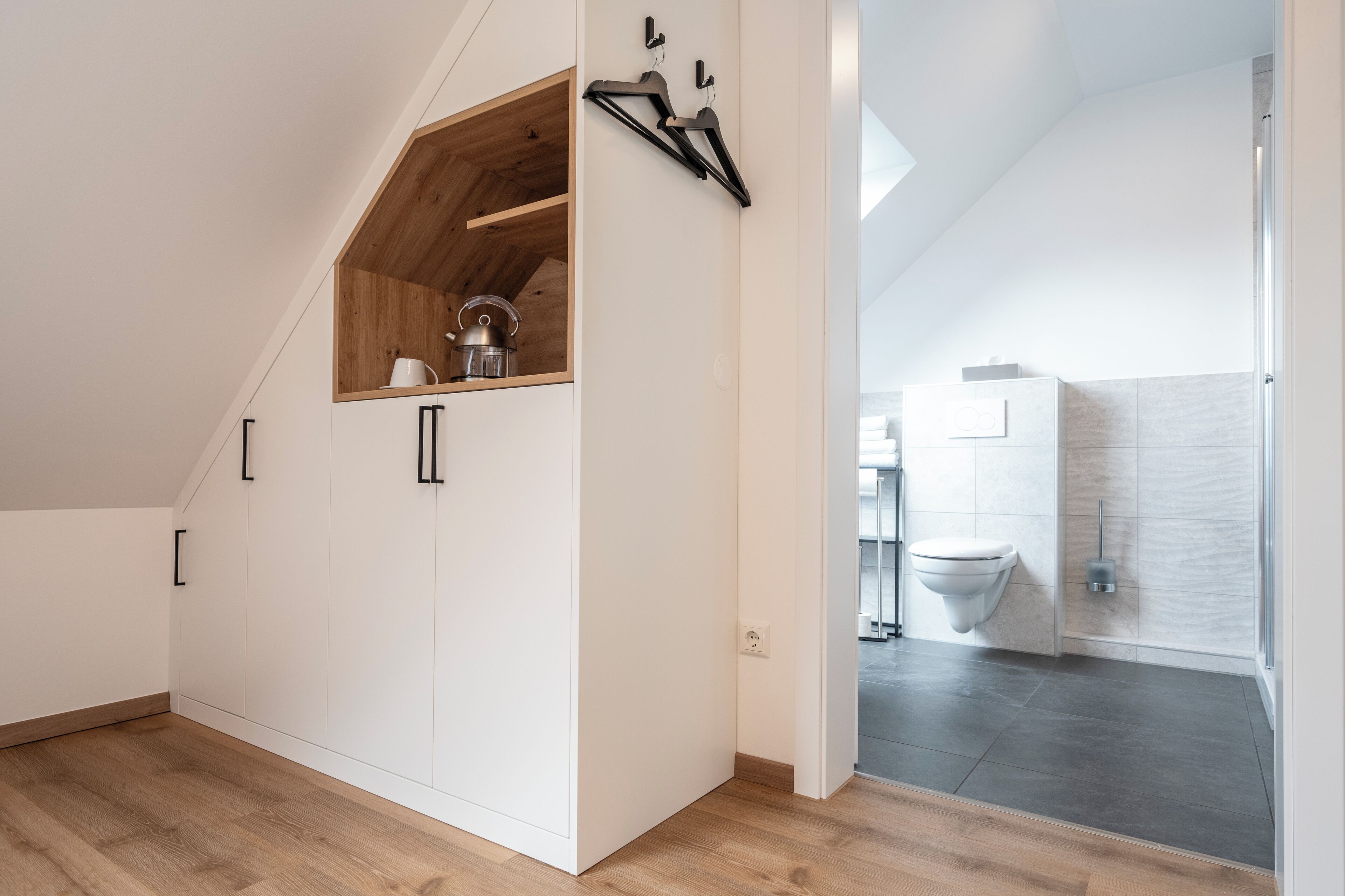 Un intérieur moderne avec une chambre à coucher de style loft, un lit mezzanine en bois, des meubles blancs et une vue sur la salle de bain.