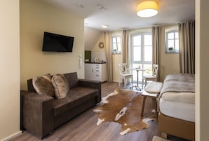 A modern living room with a sofa, a coffee table, and a television mounted on the wall.