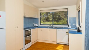 Eine moderne Küche mit Einbauofen, Geschirrspüler und einem Fenster mit Blick auf Grünflächen.