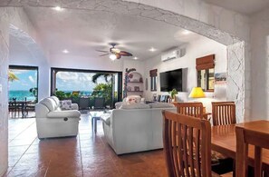 Relax in this stylish living area with a sofa set, dining table, and flat-screen TV, offering a view of the ocean.