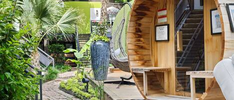 A wooden pod-style room with a built-in fan, a staircase, and a view of a lush garden.