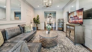 A living room with a leather sofa, a round coffee table, and a TV on a wooden cabinet.