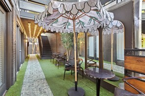 An indoor seating area with tables and chairs, a decorative umbrella, and a staircase in the background.