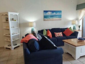 A living room with a sofa, a coffee table, and a bookshelf.
