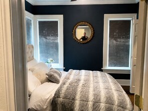 A bedroom with a bed, two windows, a mirror, and a door. - A charming one-bedroom space with comfortable interiors and a peaceful atmosphere, offering a welcoming place to relax, recharge, or settle into your Dallas stay.🎡 STAY MINUTES FROM THE STATE FAIR OF TEXAS! 🎡 (Dallas)