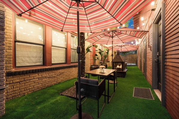 A patio area with striped umbrellas, a fire pit, and a brick wall. - A peaceful two-bedroom escape with comfortable interiors, thoughtful details, and plenty of room to settle in, relax, or enjoy a productive Dallas stay.🎡 STAY MINUTES FROM THE STATE FAIR OF TEXAS! 🎡 (Dallas)