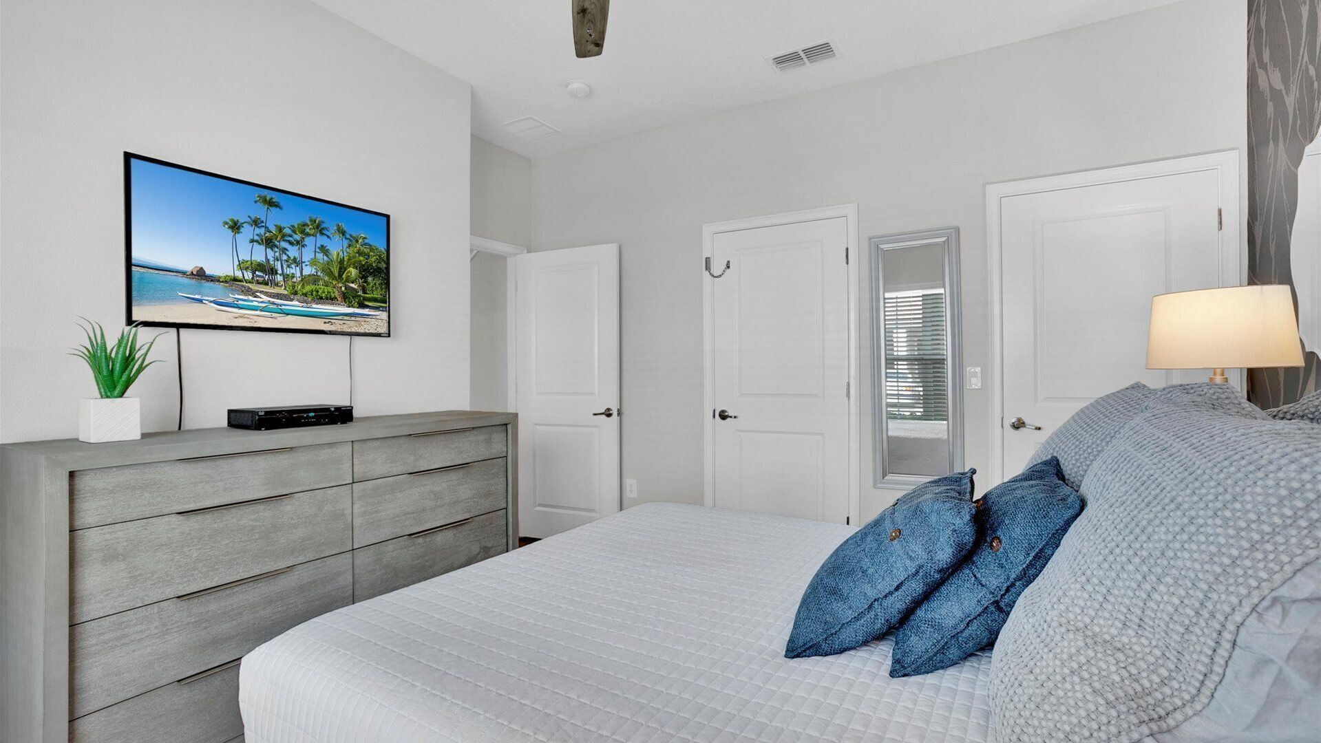 Une chambre à coucher avec un lit, une commode, un téléviseur et une porte.