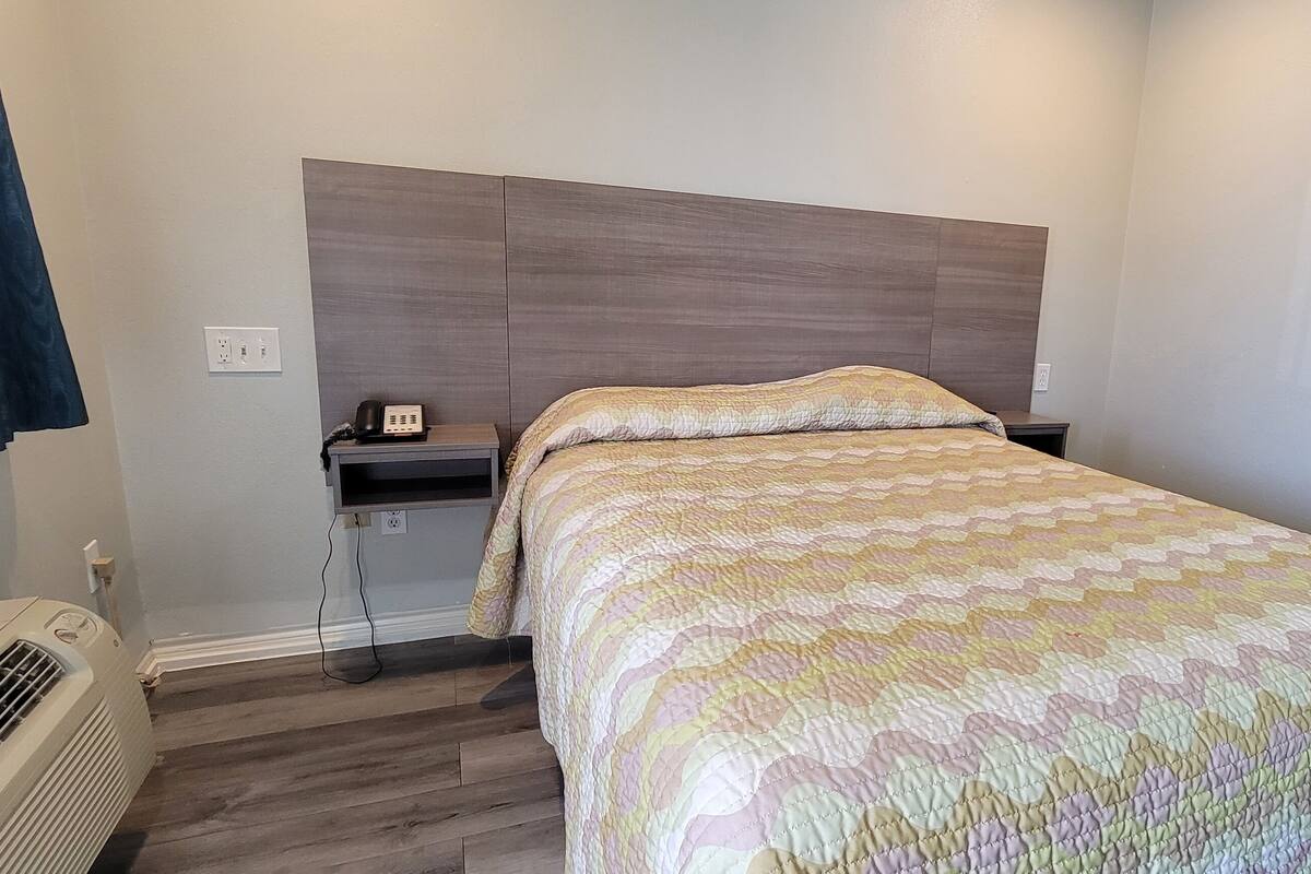 Een keurig opgemaakt slaapkamer met een bed, nachtkastje en een verwarming.