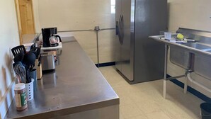 A kitchen with a stainless steel refrigerator, a coffee maker, and utensils on the counter.
