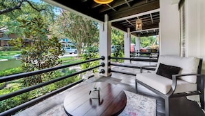 A balcony with a round table, two chairs, and a hanging light fixture. - Spacious 1-bed executive condo on Dallas’ historic Swiss Avenue. Enjoy the porch access, high-speed Wi-Fi, king bed with Egyptian-cotton linens, and modern design with upscale finishes—perfect for morning coffee, remote work, or relaxing evening (Dallas)