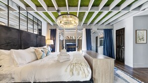 A modern bedroom with a large bed, a chandelier, and a unique ceiling design.