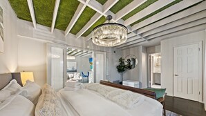 A bedroom with a large bed, a chandelier, and a ceiling with green grass-like panels. - Spacious 1BR/1BA condo in Dallas’ Historic Munger Place with a private fenced yard, king luxury hybrid mattress, Egyptian-cotton linens, fireplace, Smart TV, high-speed Wi-Fi, Alexa concierge, and a fully equipped gourmet kitchen. (Dallas)