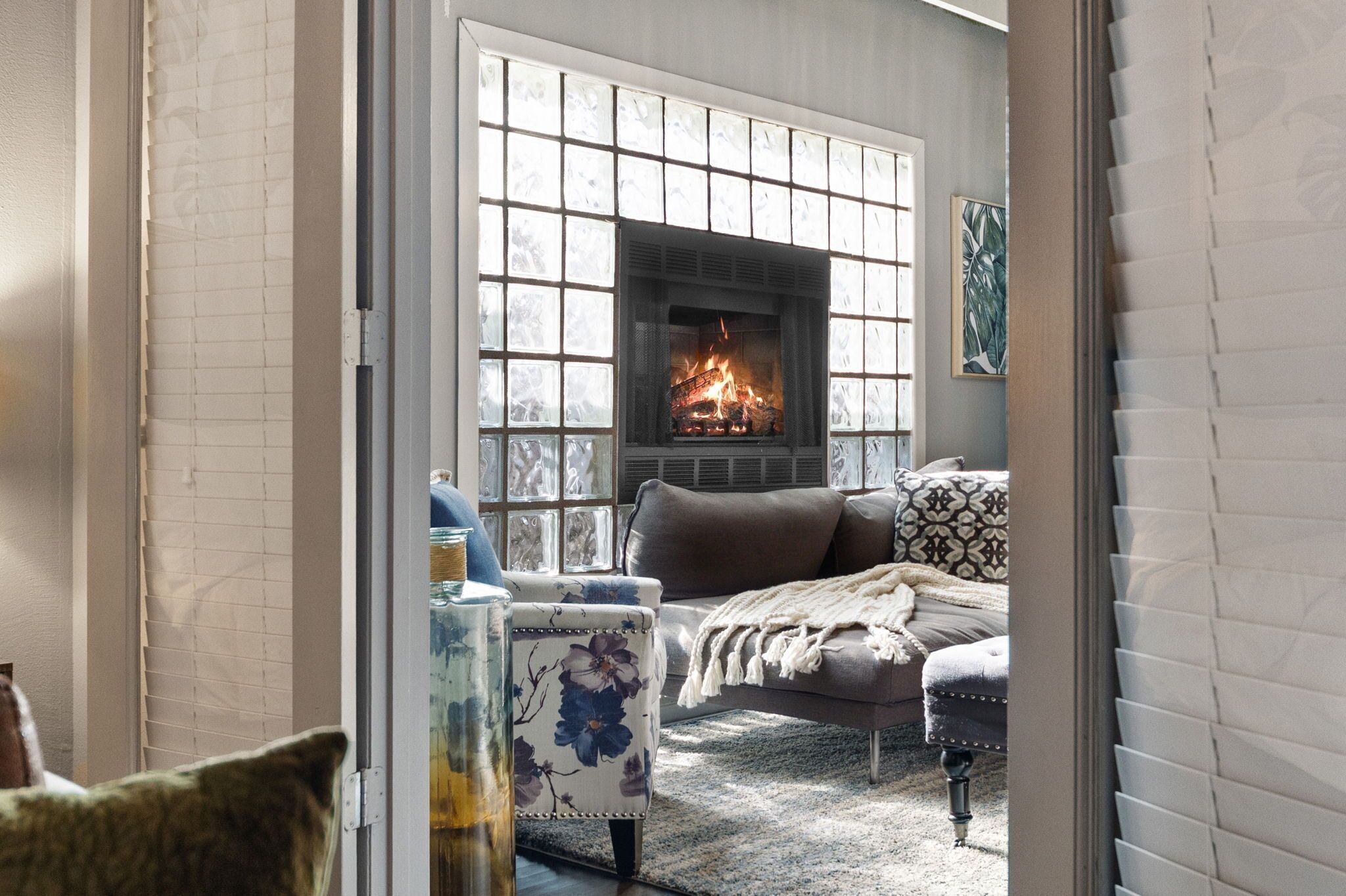 A cozy living room with a fireplace, a sofa, and a patterned armchair.