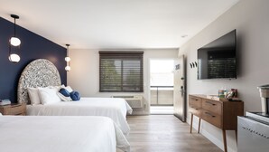 Ein modernes Schlafzimmer mit zwei Betten, einem großen Spiegel, einem Flachbildfernseher und einer Holzkommode.