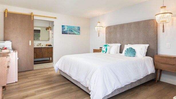 Ein Schlafzimmer mit einem großen Bett, Nachttischen, einem Kleiderschrank und einem durchgegangenen Tür sichtbaren Badezimmer.