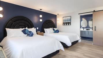 Une chambre moderne avec deux lits, un mur d’accent bleu foncé et un plancher en bois.