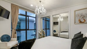 Une chambre d’hôtel avec un grand lit, un lustre, une télévision, un balcon avec vue et un miroir.