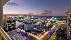 Un port de plaisance avec des bateaux amarrés, un restaurant situé au bord de l’eau et une vue sur les gratte-ciel de la ville.