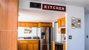 A kitchen with wooden cabinets, stainless steel appliances, and a 'KITCHEN' sign. - Newley remodeled and furnished home! (fresno)