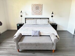 A bedroom with a bed, two bedside tables, a wall art piece, and a bench. - Newley remodeled and furnished home! (fresno)