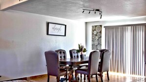 A dining area with a round table and six chairs, a framed quote on the wall, and a patterned wall decoration. - Newley remodeled and furnished home! (fresno)
