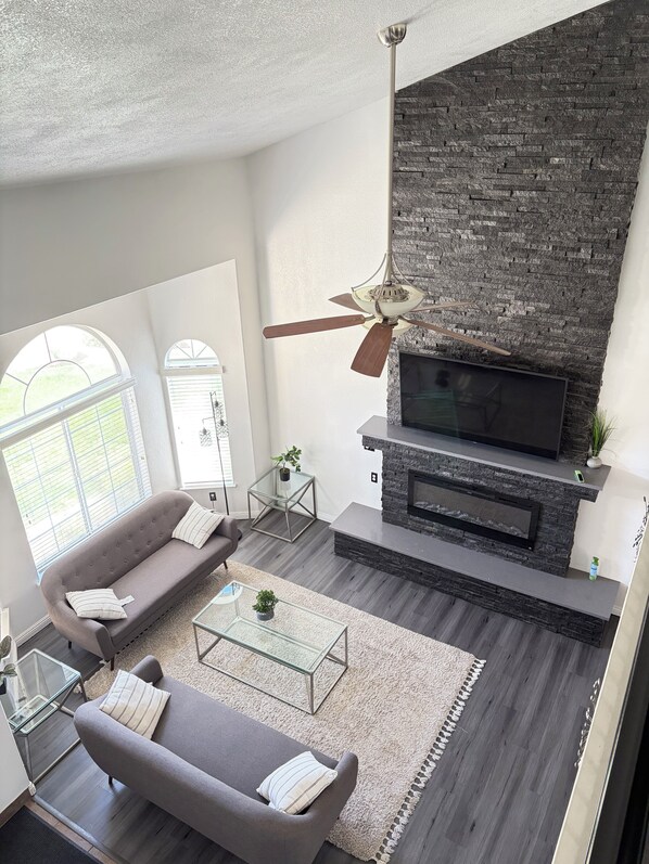 A modern living room with a fireplace, a sofa, a coffee table, and a television.
