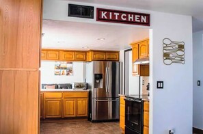 A kitchen with wooden cabinets, stainless steel appliances, and a 'KITCHEN' sign.