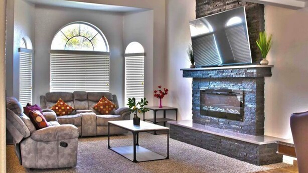 A modern living room with a fireplace, two sofas, a coffee table, and a TV mounted on the wall. - Newley remodeled and furnished home! (fresno)
