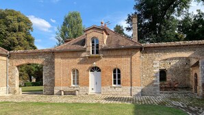 A historic building with a brick facade, arched windows, and a stone chimney. - Country house next to a golf course, in the Fontainebleau region. (Voulx)