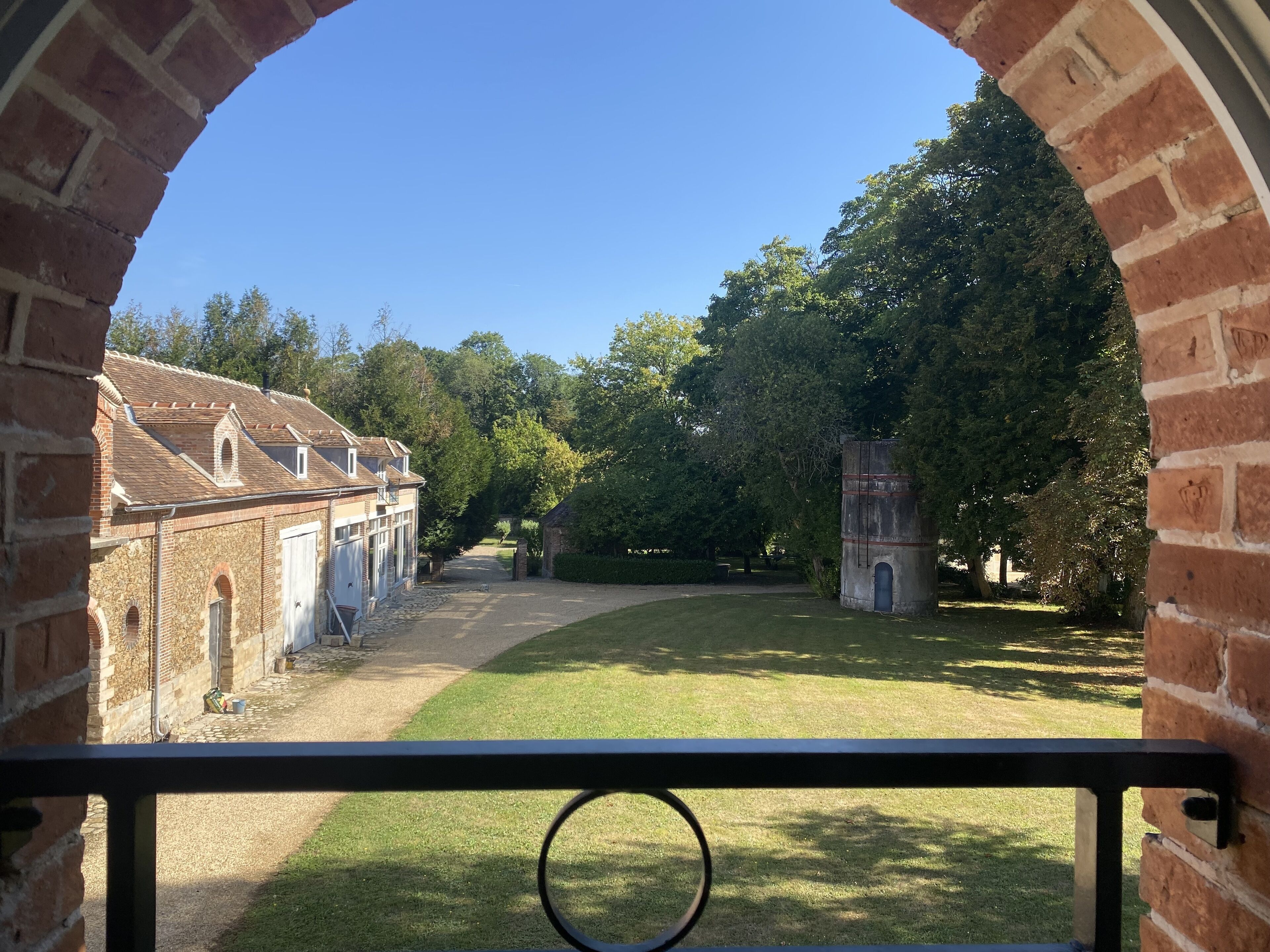 Une cour avec un bâtiment en briques, une pelouse verdoyante et des arbres.