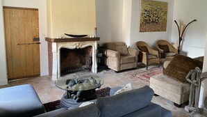 A living room with a fireplace, two sofas, a coffee table, and a rug. - Country house next to a golf course, in the Fontainebleau region. (Voulx)