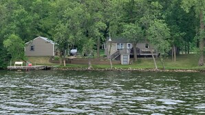 A lakeside cabin with a dock, surrounded by dense forest.