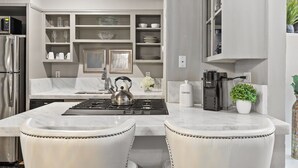 Una cocina moderna con una isla central, electrodomésticos de acero inoxidable y armarios blancos.