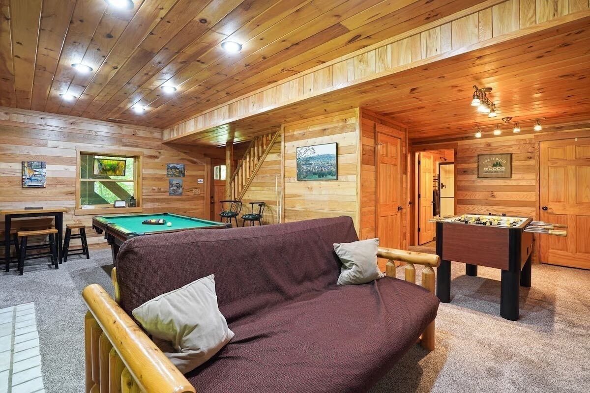 A cozy room with a pool table, a foosball table, and a sofa.