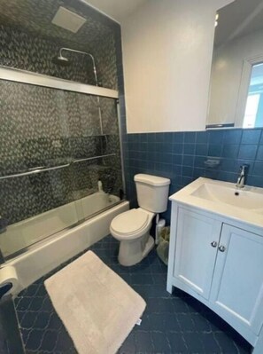 Bathroom features a glass-enclosed tub, separate toilet, and a white sink with a cabinet.