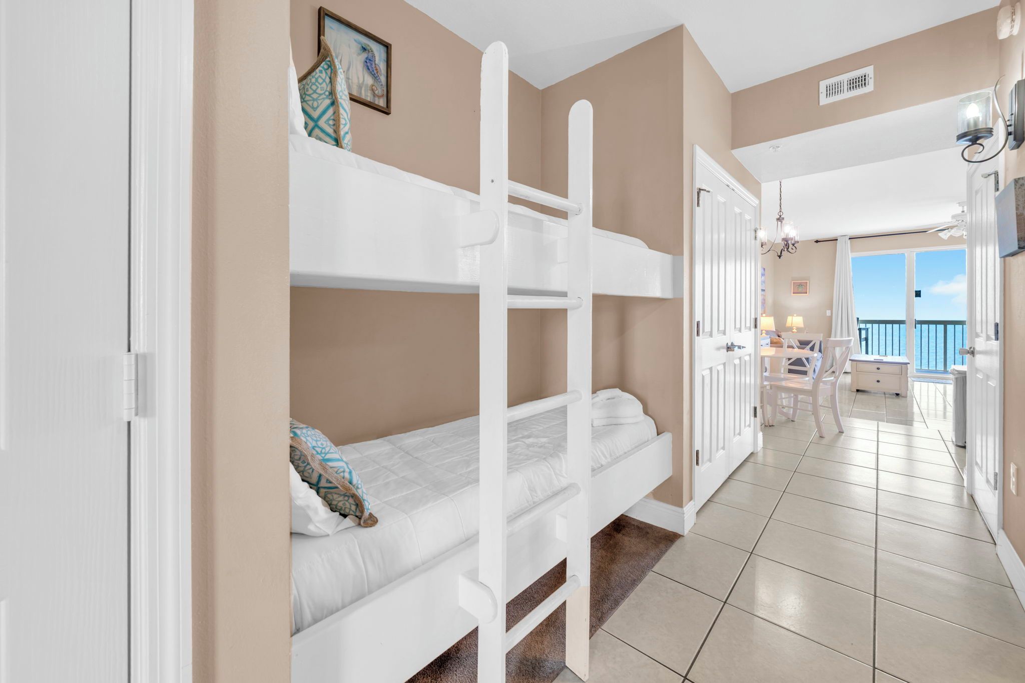 Una habitación con literas, una puerta que da a un balcón y vista al mar.