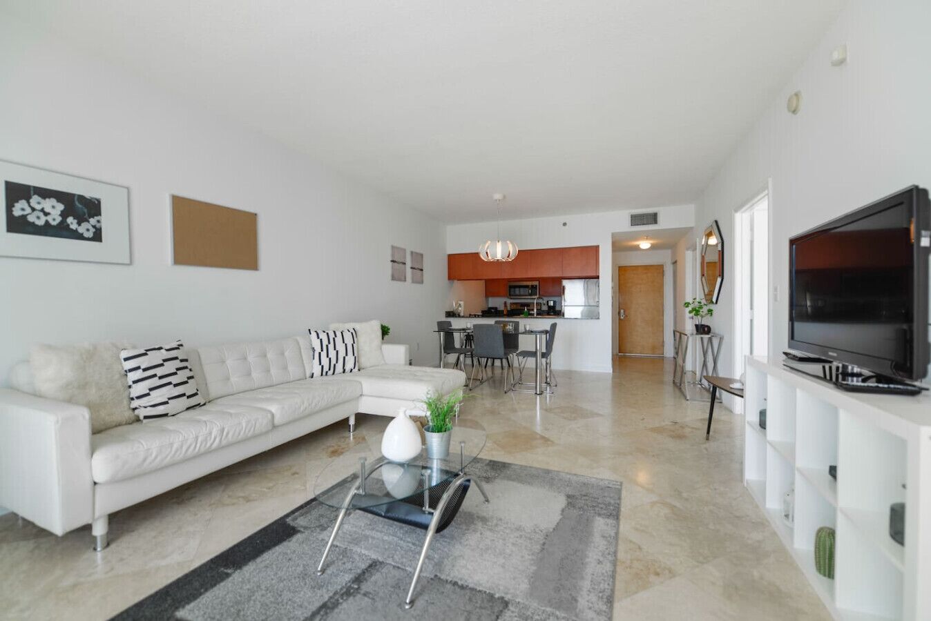 A modern living room with a white sofa, a glass coffee table, and a flat-screen TV.